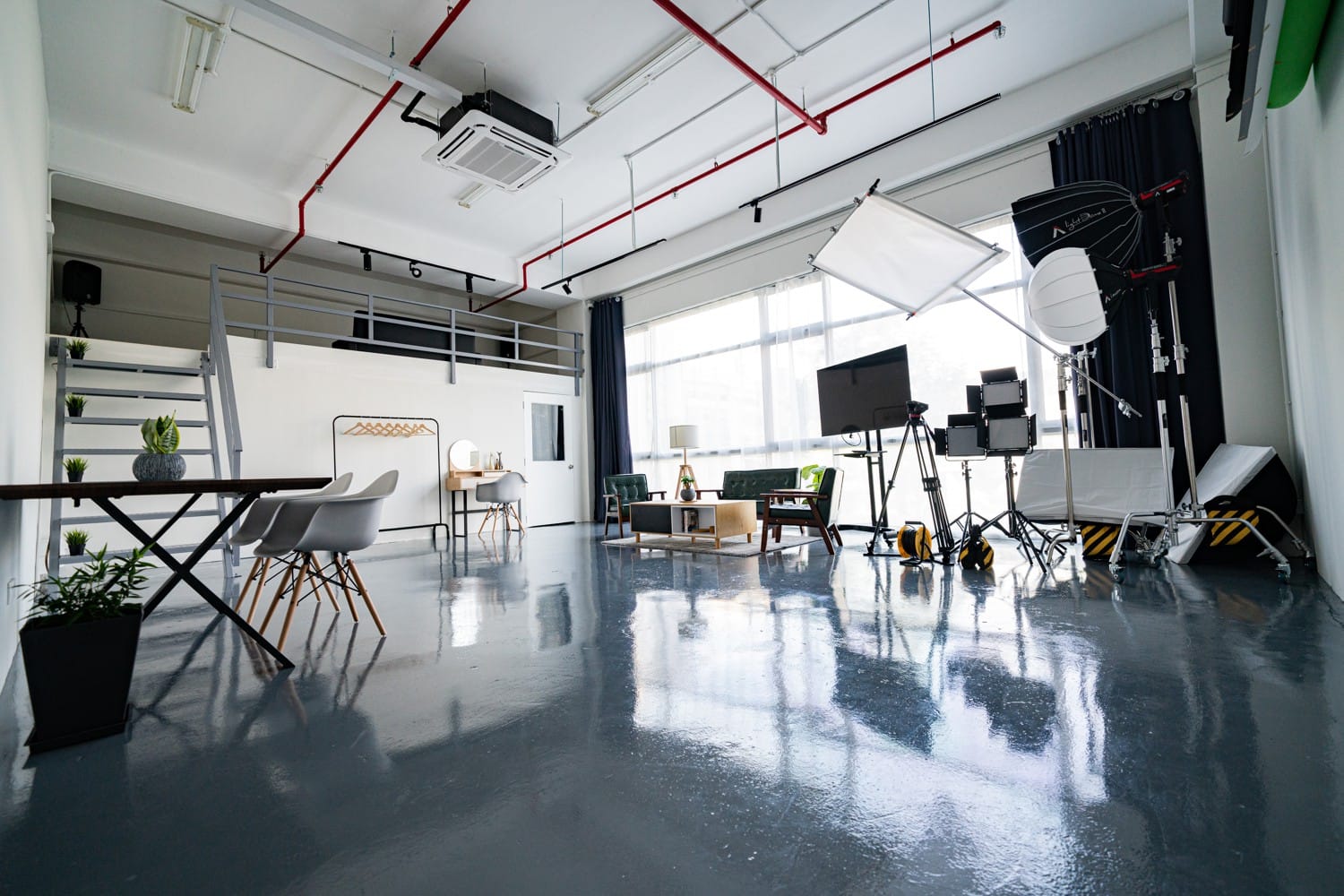 A photography studio with a lounge set, a camera tripod and a reflector.